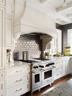 The range area is this room's focal point.  With two large decorative brackets, the range hood echoes the furniture-style details featured throughout the room on the cabinetry and the island.