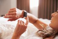 Woman looking at her watch after waking up.