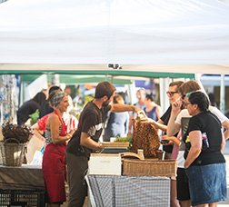 Persones que compren i venen en un mercat de pagès.