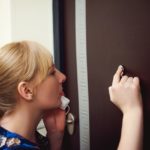 Woman anxiously looking through peephole on the phone