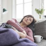 Woman who appears to be sick and resting on her couch