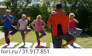 Купить «Rear view of Caucasian male trainer training senior people in performing yoga at the garden of n 4k», видеоролик № 31917851, снято 22 ноября 2018 г. (c) Wavebreak Media / Фотобанк Лори