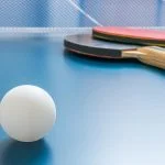 White ball for table tennis or ping pong on wooden table.