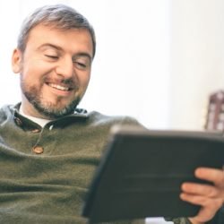 Man using digital smart home tablet on the couch