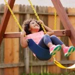 Kid toddler girl swinging on a playground swing