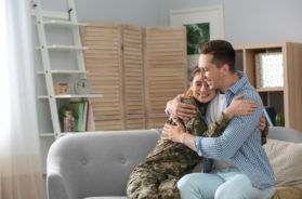 Woman in military uniform with her husband on sofa at home