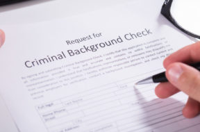 Person Hand Filling Criminal Background Check Application Form