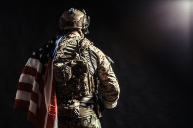 Soldier holding machine gun with national flag