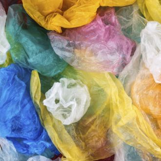 On voit plusieurs sacs en plastique de différentes couleurs disposés en vrac sur une surface.