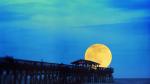 Full moon on the horizon at the end of a dock.