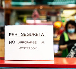 Taulell d'un comerç amb aquest cartell "Per seguretat, no apropar-se al mostrador"