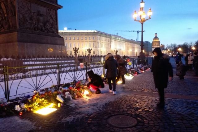 Люди несли цветы к мемориалу на Дворцовой площади.