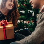 Young couple celebrating Christmas by exchanging gifts.