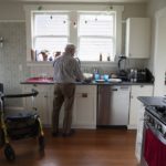 Senior man doing dishes in his kitchen with his walker