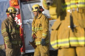 Male firefighters talking with each other with colleague in the foreground