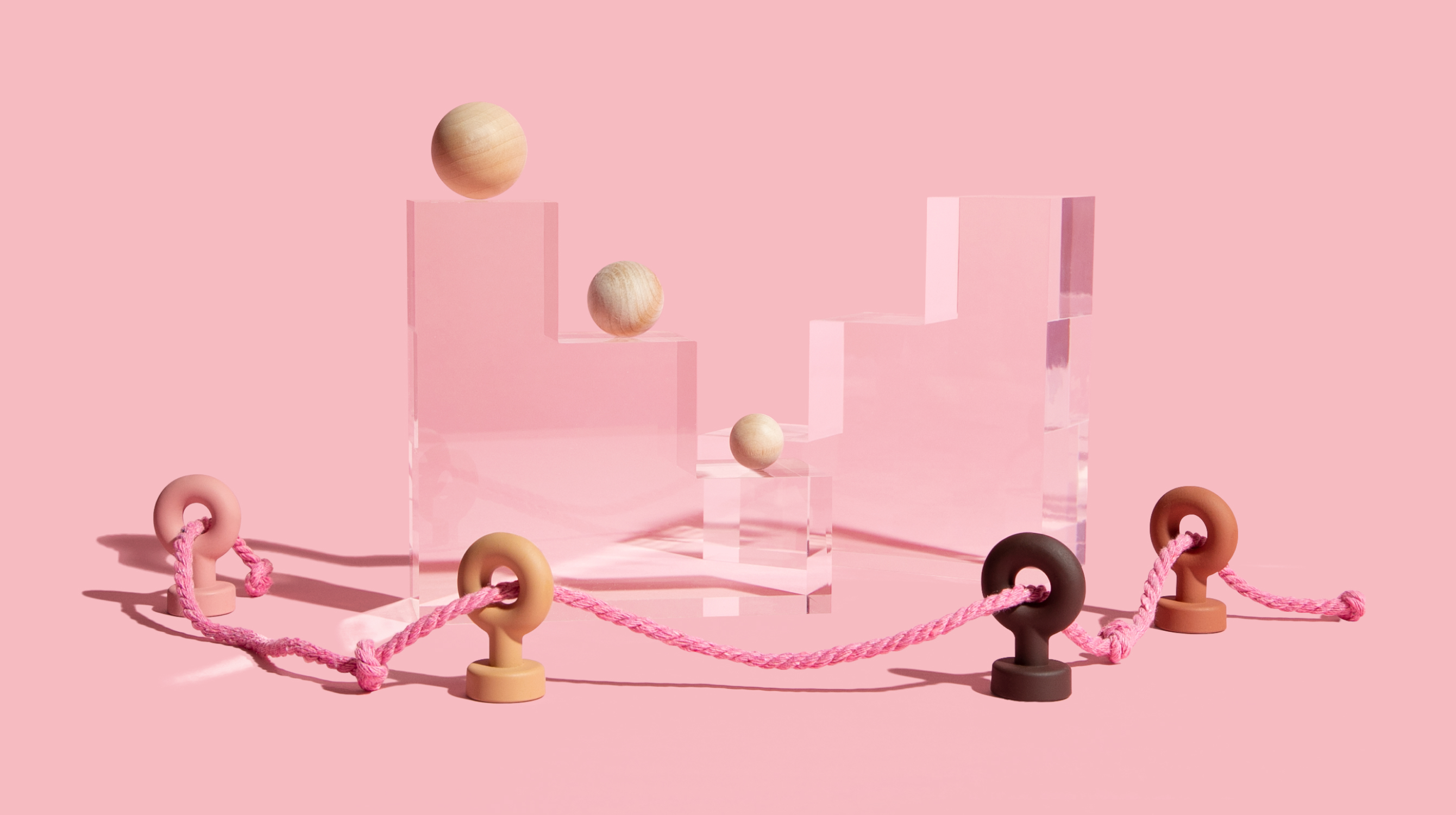 Wooden balls on pedestals with pink rope going through hooks around it