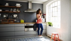 Pregnant woman in tidy modern kitchen in a renovated old building