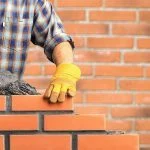 mason lays plaster between brick