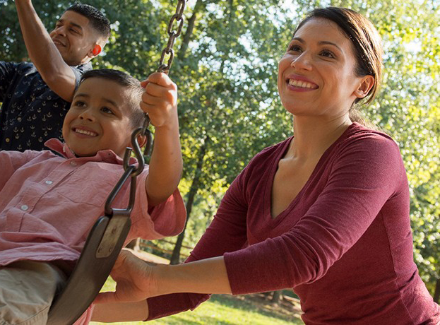 Mobile Image for Male Military Spouse pushing child on swing with military wife