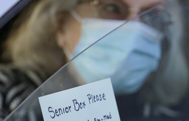 A woman displays a note for a “Senior Box” during a food distribution outside the Catholic Community Services of Utah Friday, Nov. 20, 2020, in Ogden, Utah. (AP Photo/Rick Bowmer) UTRB101 UTRB101