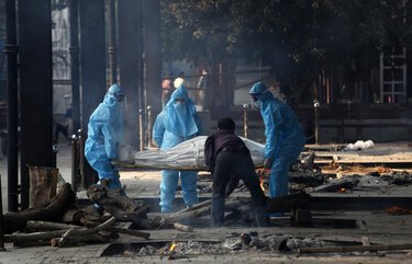 Health workers in personal protective equipment carry the body of a COVID-19 victim for cremation in New Delhi, India, Thursday, Nov. 19, 2020. India’s confirmed coronavirus caseload is expected to surpass 9 million on Friday as authorities in New Delhi battle to slow down the surge of infections in the city by increasing testing. The country’s overall tally of confirmed cases is currently the second largest in the world behind the United States. (AP Photo/Manish Swarup) XMS102 XMS102