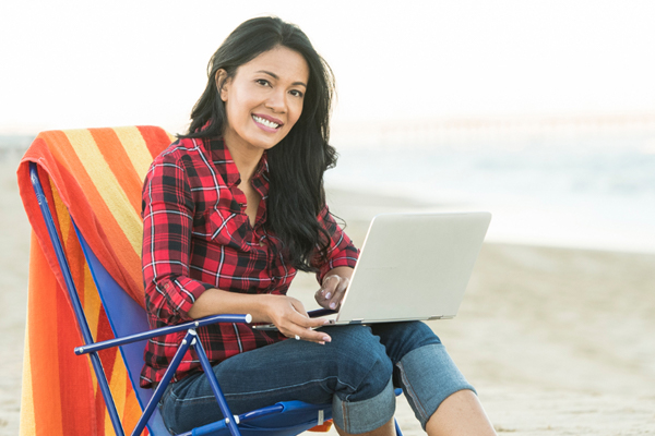 Photo of Chanda sitting on the beach with her laptop