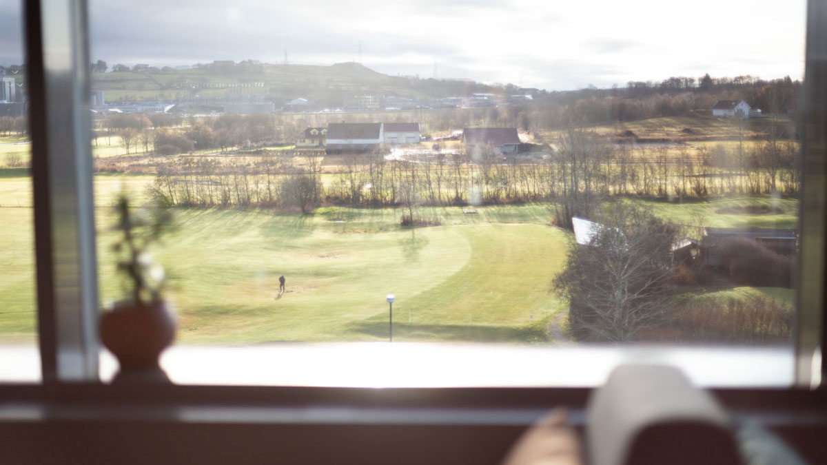 Utsikt til en golfbane igjennom store vinduer.