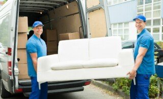 two movers with sofa loading it into a van