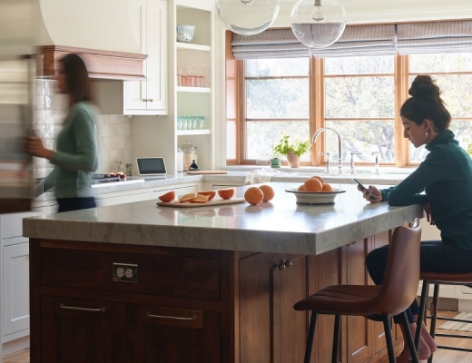 Woman opening fridge, other woman on phone, Vivint Smart Hub on the counter