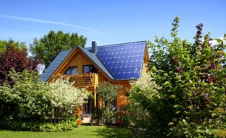 Home in a lush, green garden with a seamless, solar roof