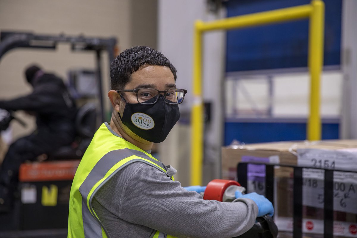 A Los Angeles Regional Food Bank employee with a face mask poses for a picture in a warehouse.