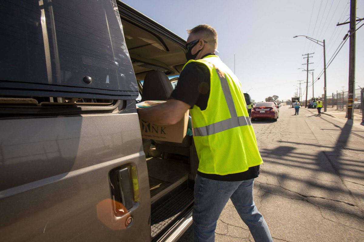 A volunteer loads a parked car with food kits at a drive-through food distribution hosted by the Los Angeles Regional Food Bank.