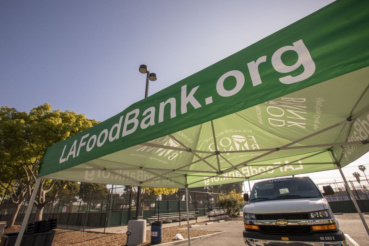 A close up of a tent with the website of the Los Angeles Regional Food Bank at a drive-through distribution.