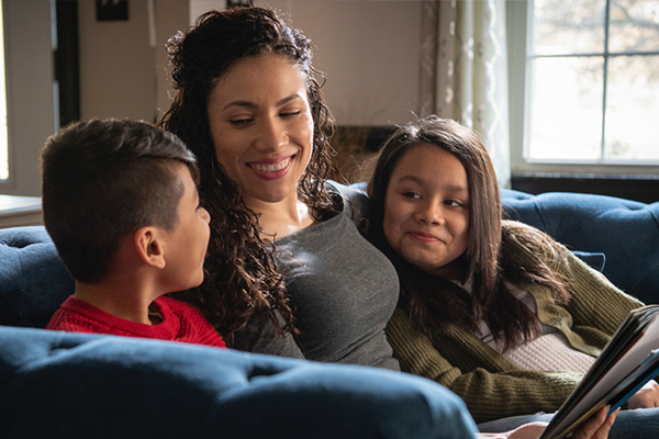 Photo of Yesli sitting on a sofa with her children