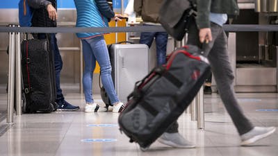 Travelers with their suitcases at a check-in counter at Munich airport. Photo by AP.