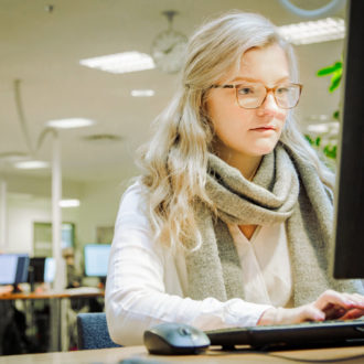 A woman types on a computer keyboard in a library.