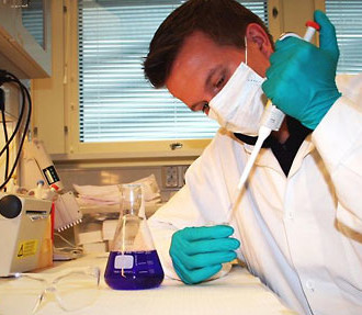 A doctor with a white coat and mask analyzing a specimen.