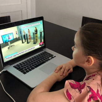 A girl watches government ministers talk about the coronavirus situation, on a laptop computer.