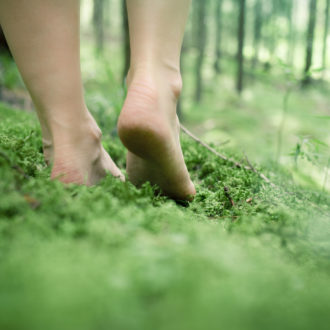 A pair of bare feet walking in the forest.