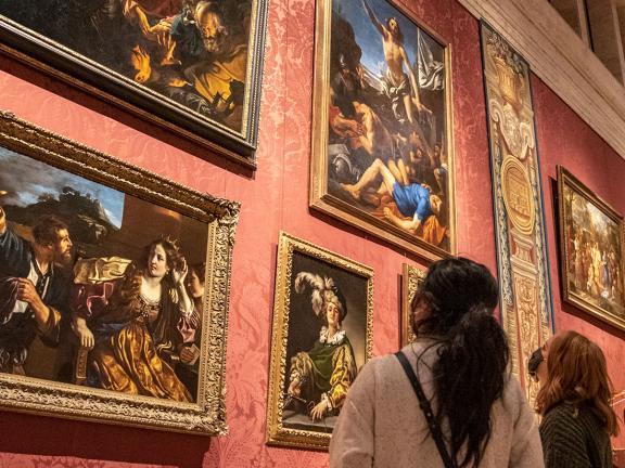 two visitors looking up at paintings hung on wall in Koch gallery