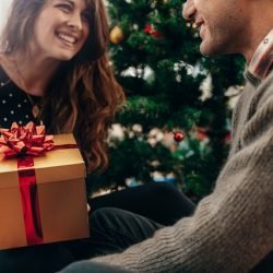 Young couple celebrating Christmas by exchanging gifts.