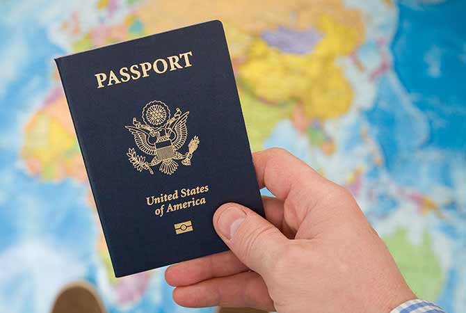 U.S. passport being held in front of world map.