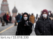 Мужчина и женщина в медицинских масках идут по Красной площади в городе Москве во время эпидемии гриппа, Россия (2020 год). Редакционное фото, фотограф Николай Винокуров / Фотобанк Лори