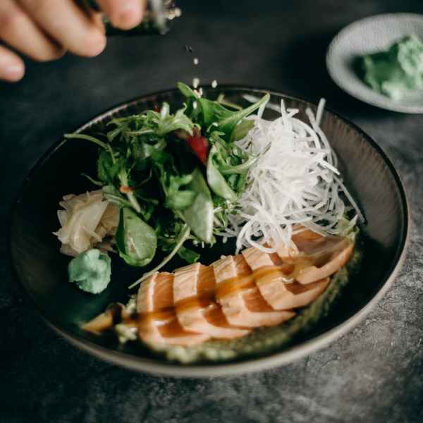 sliced meat with vegetable on black ceramic plate