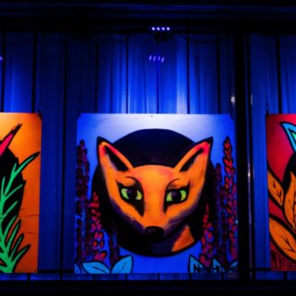 Graffiti showing a squirrel, a fox and a rabbit lit with ultraviolet light.