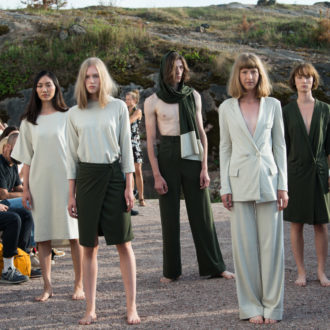 Five serious-looking models standing on an outdoor runway.