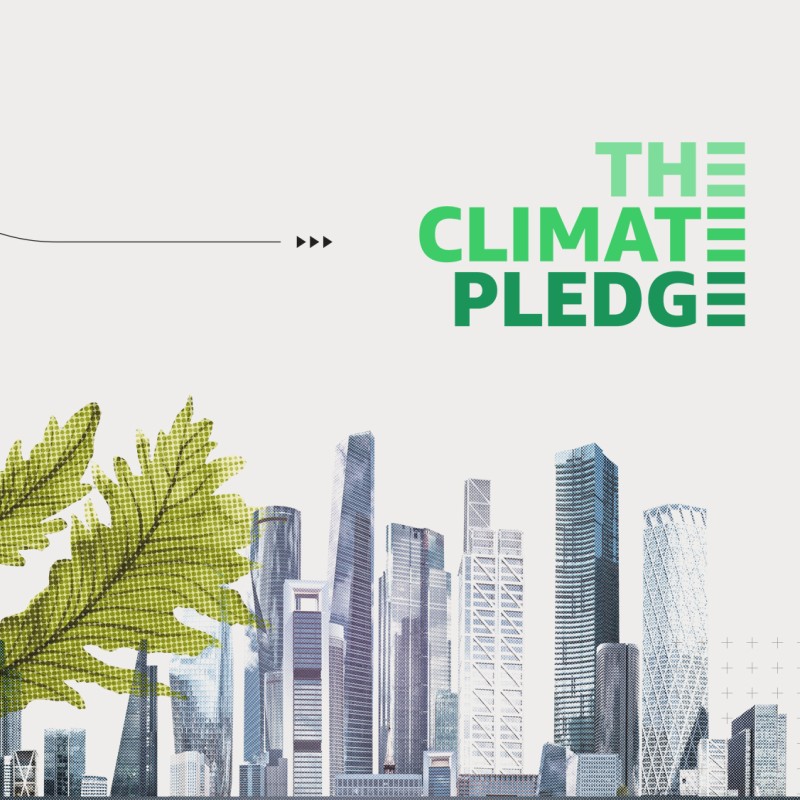 A city with tall buildings is the right backdrop of the image with The Climate Pledge in green font above it. To the left is green plant coming out from the city as tall as its buildings. To the left and behind the plant is a gray-toned drawing of the Earth. 