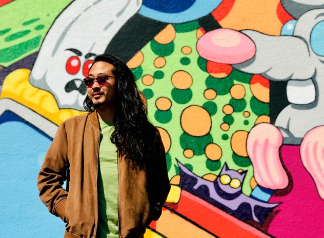 Tyler Lau stood in front of a colorful mural