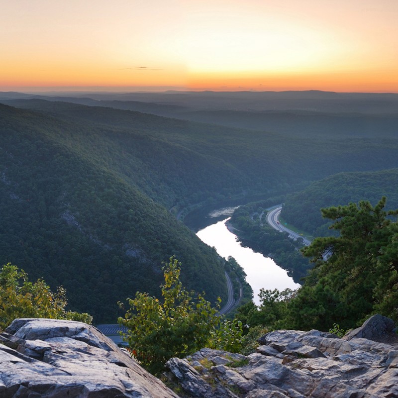 A view of the Appalacian mountains in Pennsylvania overlooking mountains, river, vegetation, in front of a sunset.