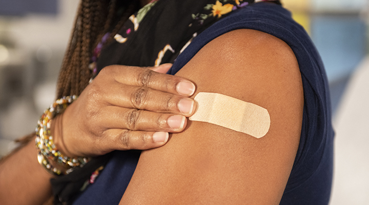 A woman showing her band-aid after vaccination.